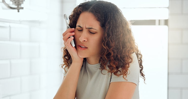 A woman holding her jaw in pain
